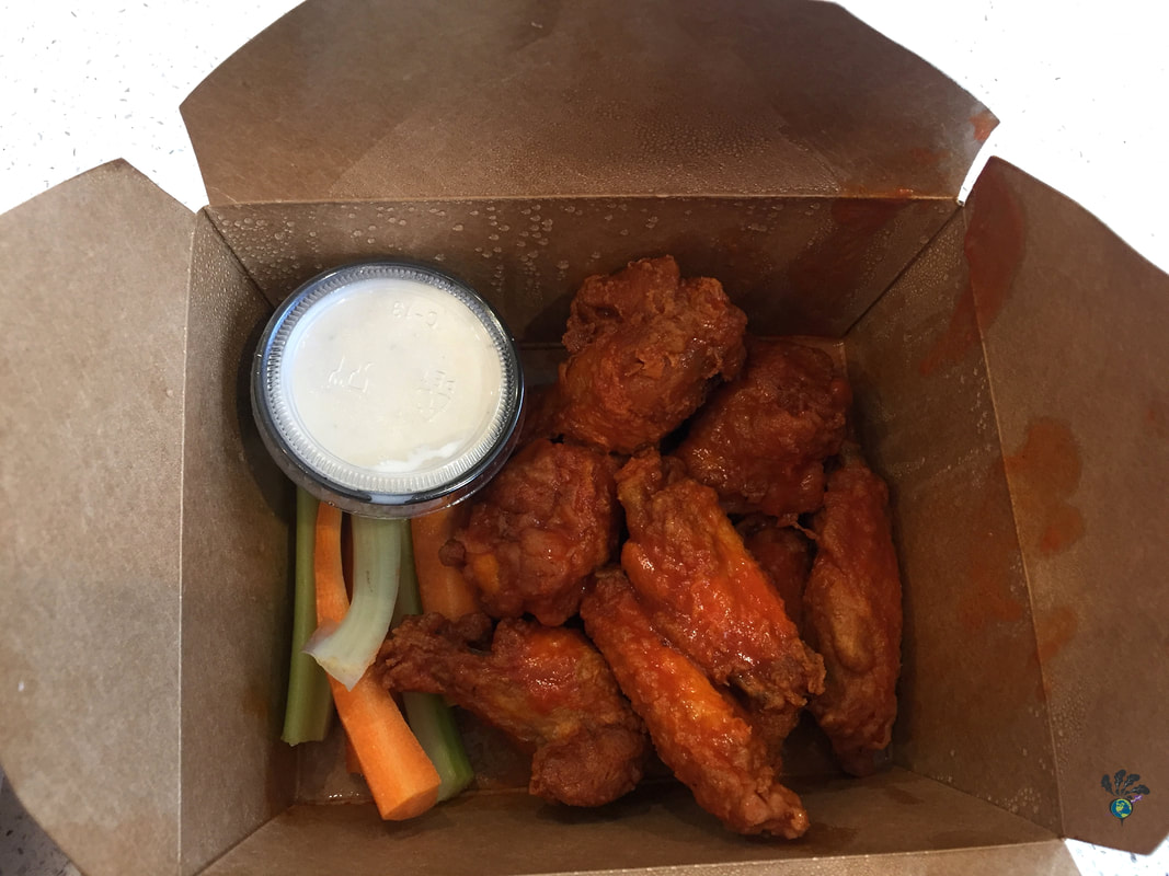 Brown cardboard take out box holding wings, dip, and veggie sticksPicture