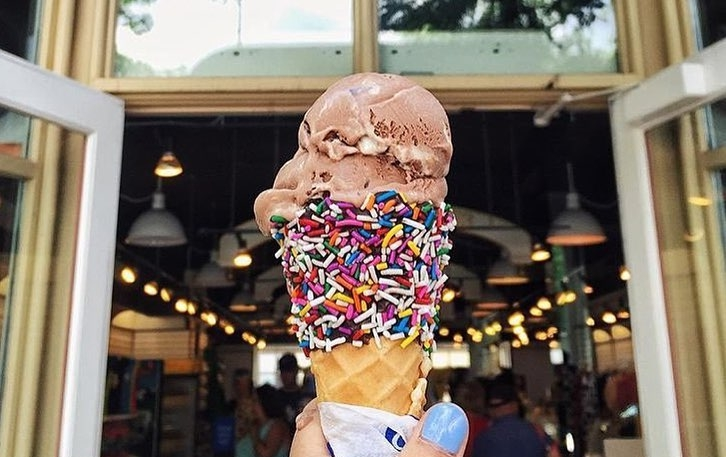 An ice cream cone with colourful sprinkles and a scoop of chocolate ice cream
