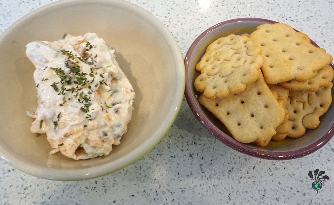 A small bowl of chip dip sits on the left, while a bowl of different crackers sits on the right
