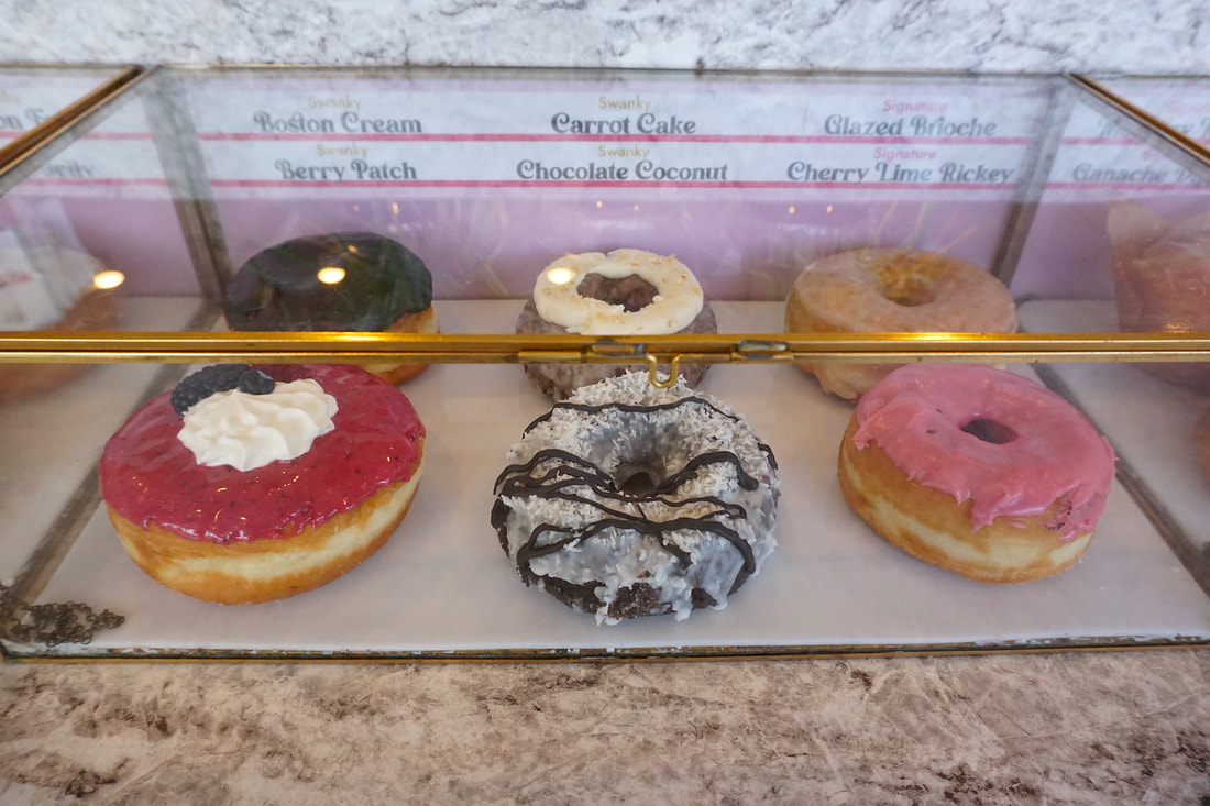 Six colourful donuts sit in a display case.