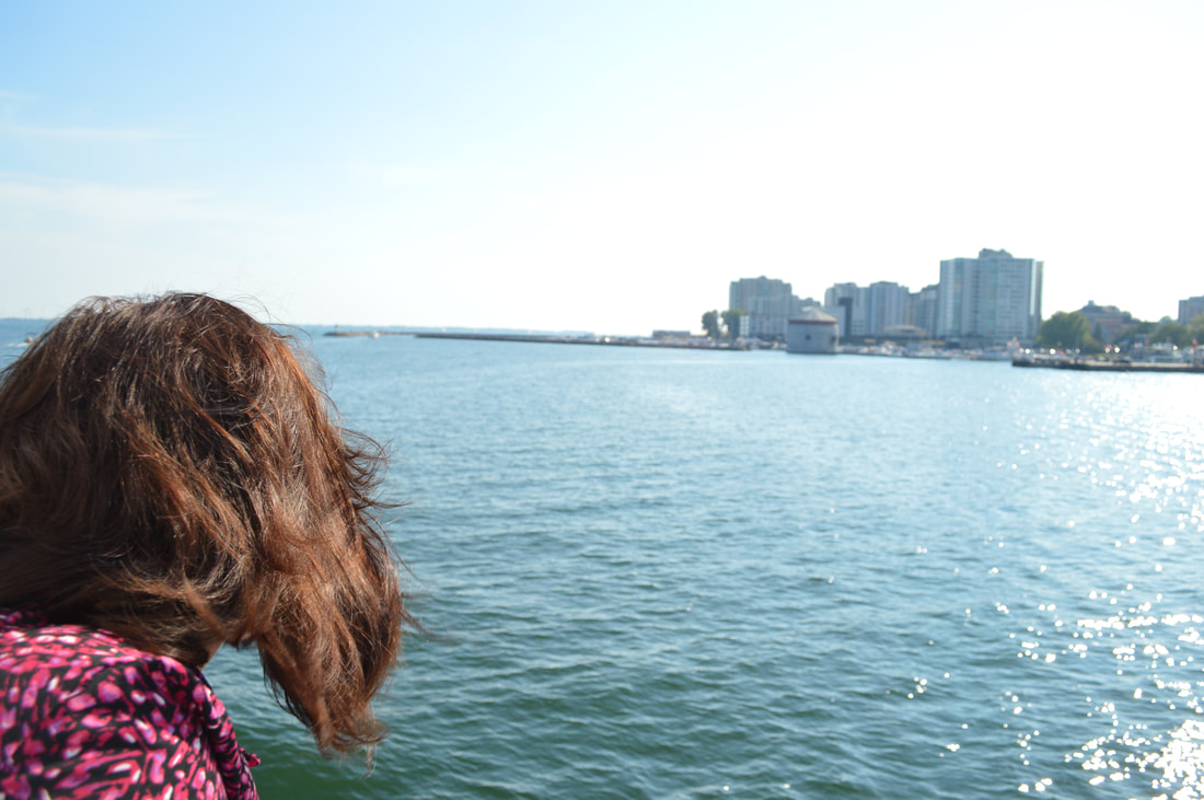 Vanessa stares out over the water while the city of Kingston in the back ground.