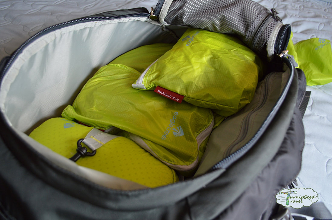 A grey backpack with bright green packing cubes inside