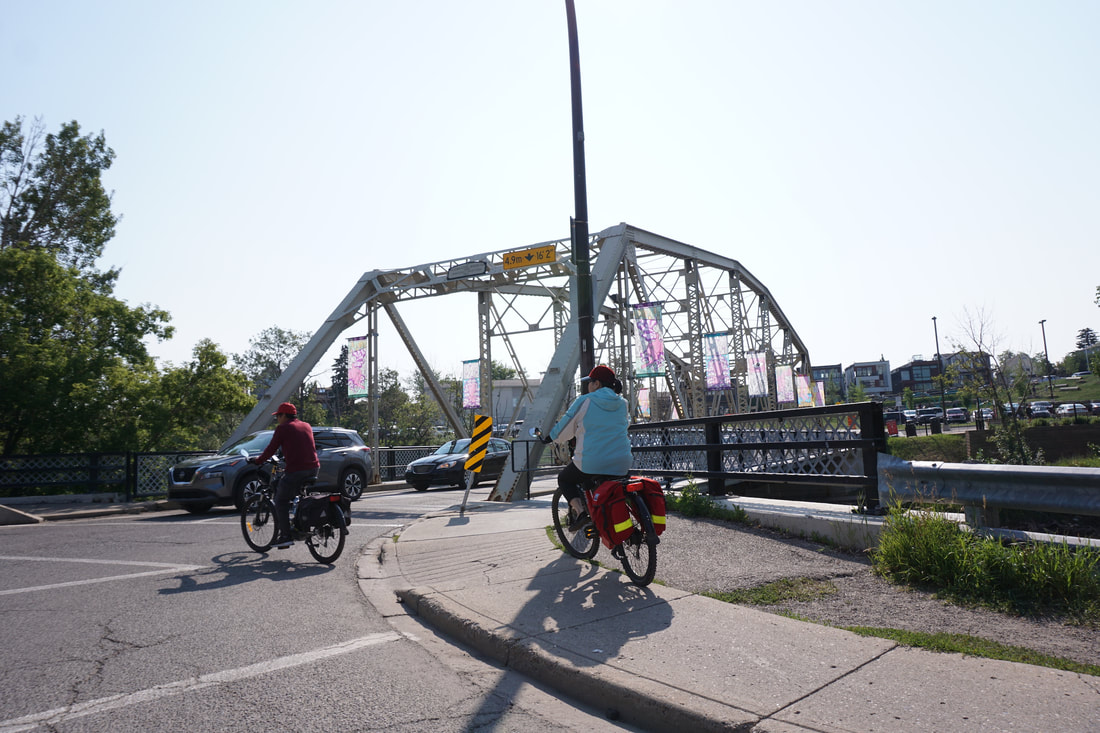 Streetscape of a bridge and two people riding a bikePicture