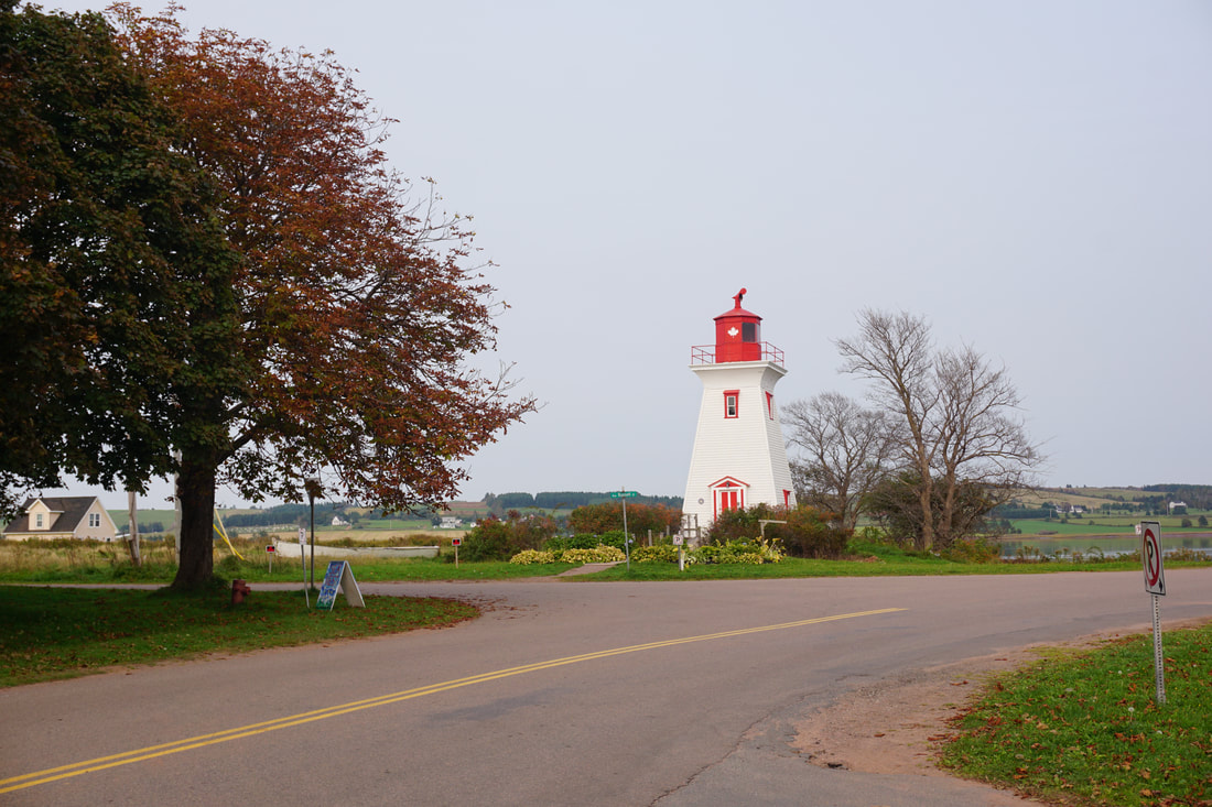 Small red and white lighthouse located near a bend in the roadPicture
