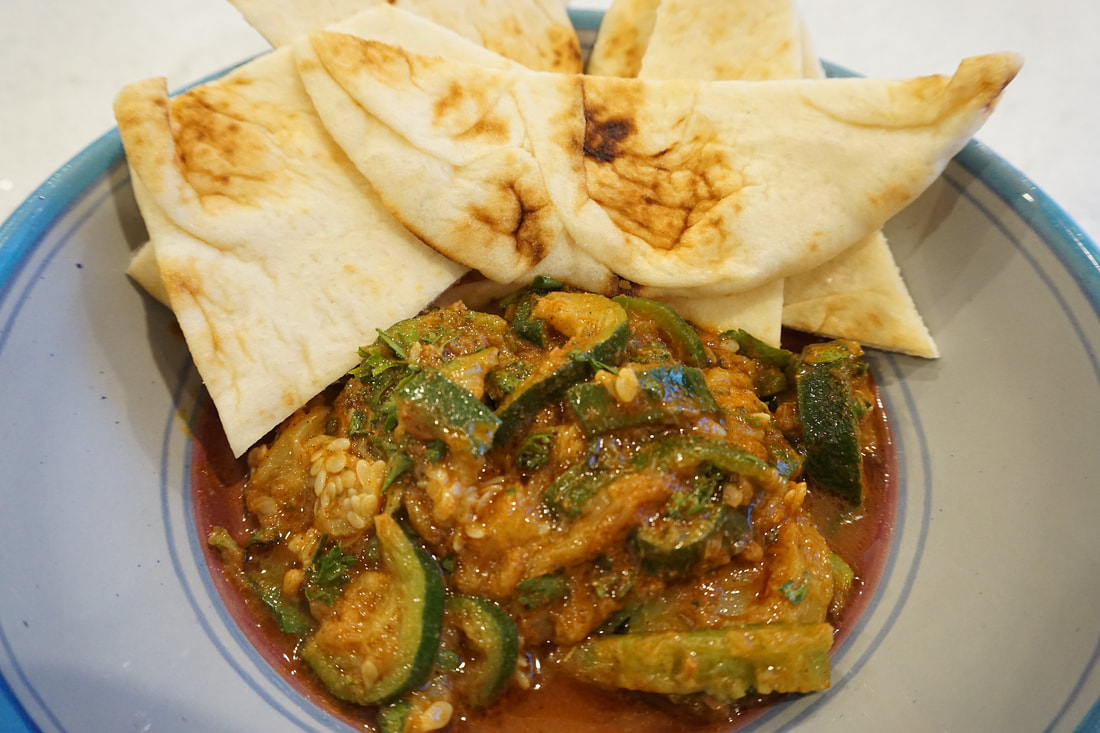 An appetizer of zucchini in a red herb sauce surrounded by piece of bread.