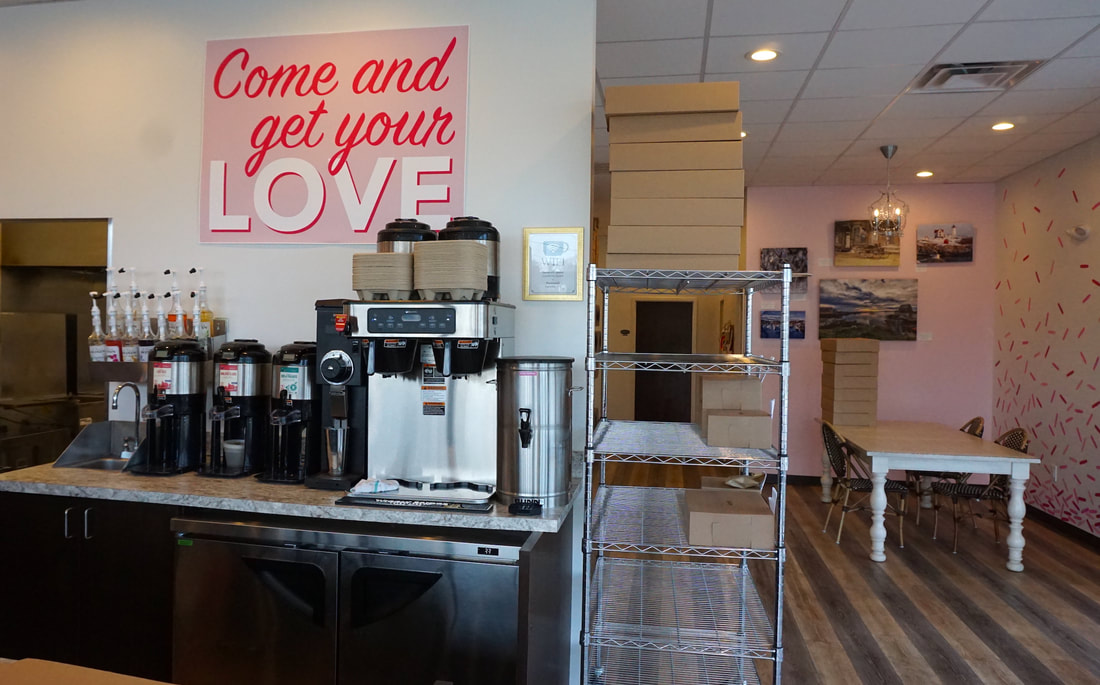 Coffee machines inside the cafe, with a large pink sign that says 