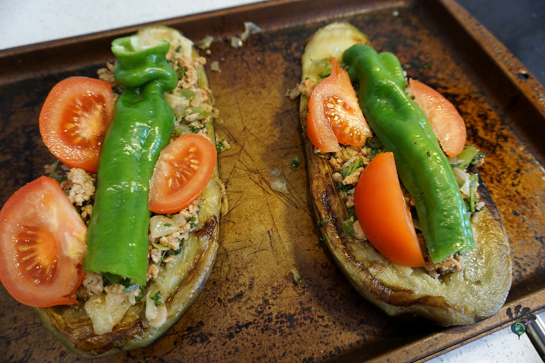 Eggplant halves stuffed with meat, tomato, and pepper sit on a cooking sheetPicture