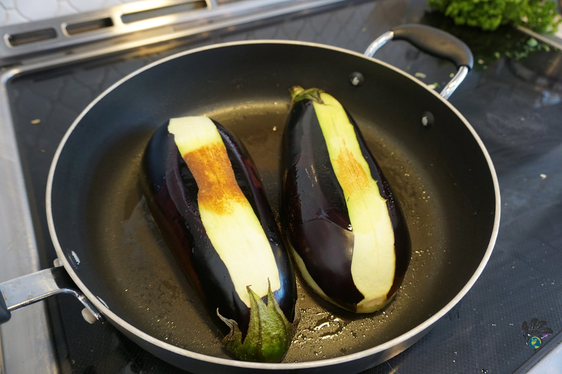 Large eggplant, cut in half and partially peeled in stripes, cooks in a frying panPicture
