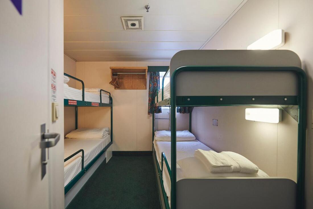 A small bunkbed room aboard the ferry, showing two sets of bunks made up with plain white linens
