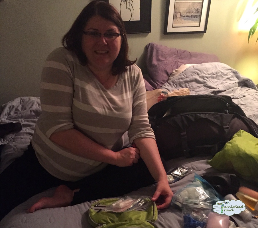 Vanessa sitting on her bed, surrounded by travel supplies and TSA friendly toiletries 
