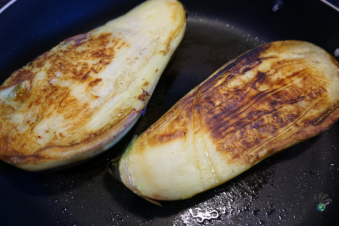 Two eggplant halves, the cut side golden from being in the frying panPicture