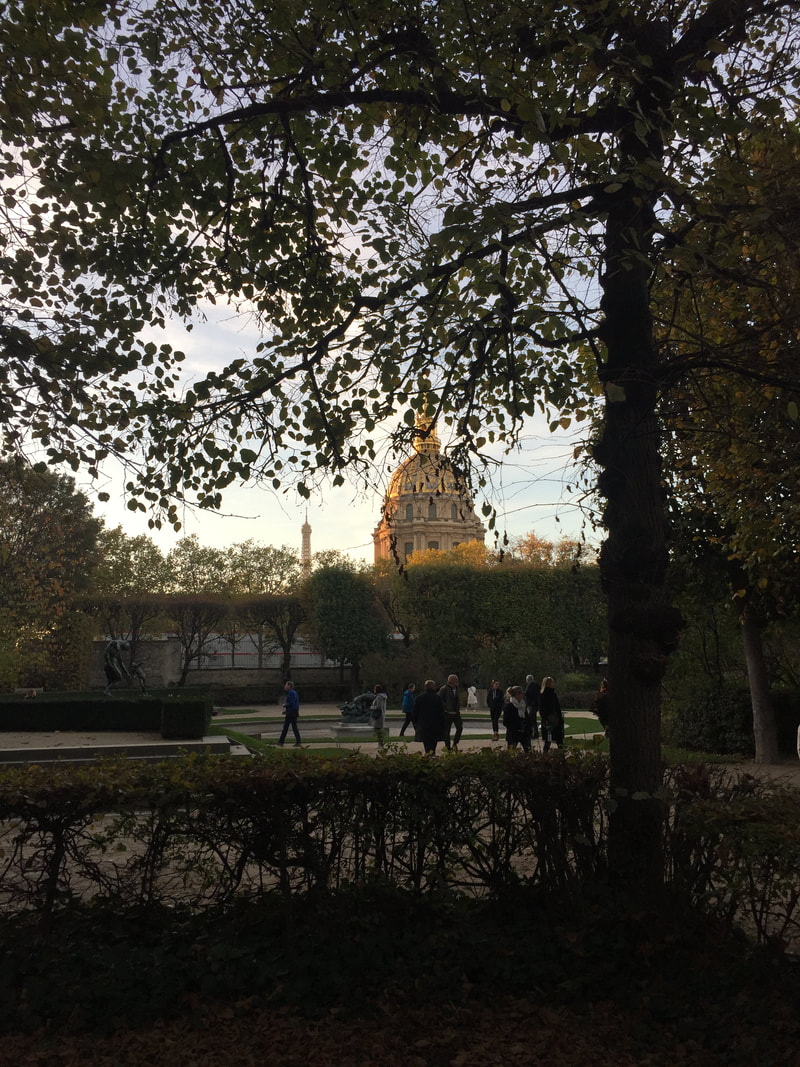 Trees of the Rodin museum garden in the foreground, golden dome of Les Invalides in the background.