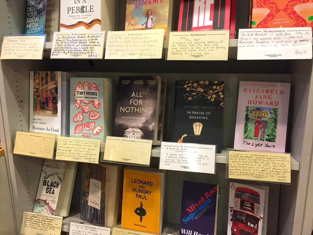 Several grey shelves showing about 15 different and diverse books with staff recommendation cards under each.Picture