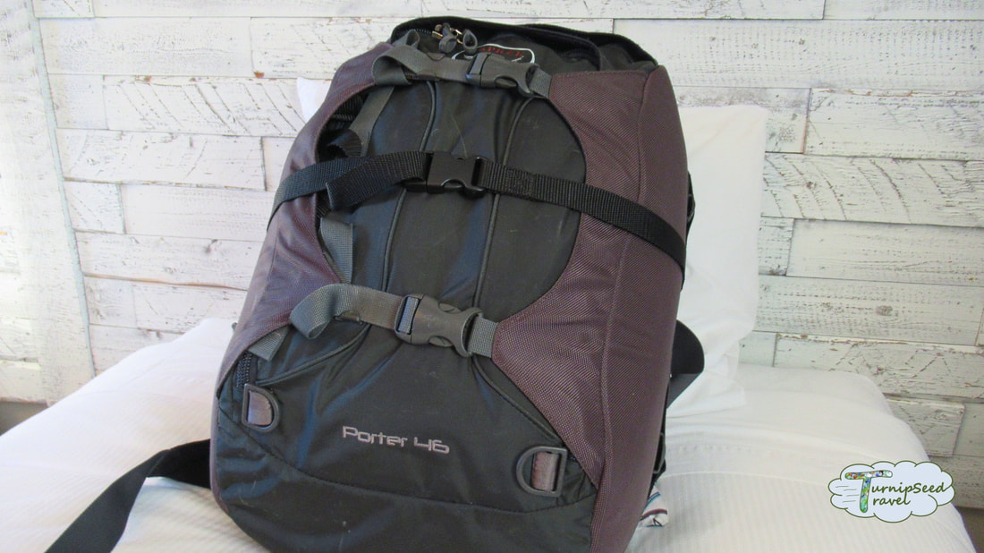 Osprey Porter 46 backpack in grey with an extra black strap around the middle. Picture
