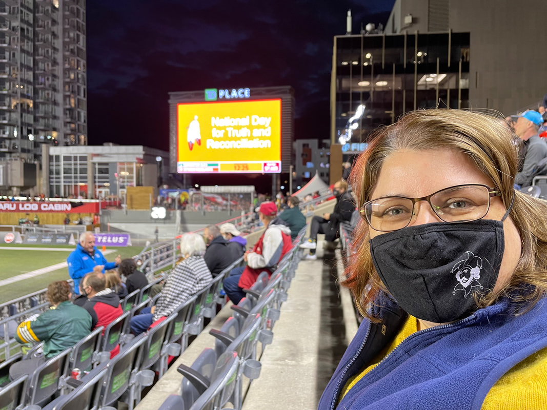 Vanessa in the stands at TD place wearing a yellow sweater and blue vestPicture