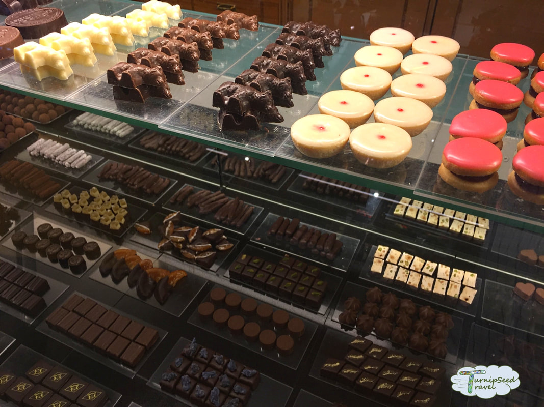 Shot of the chocolate shop display case showing many kinds of chocolates, nougat, candied orange peel, and colourful iced cookies