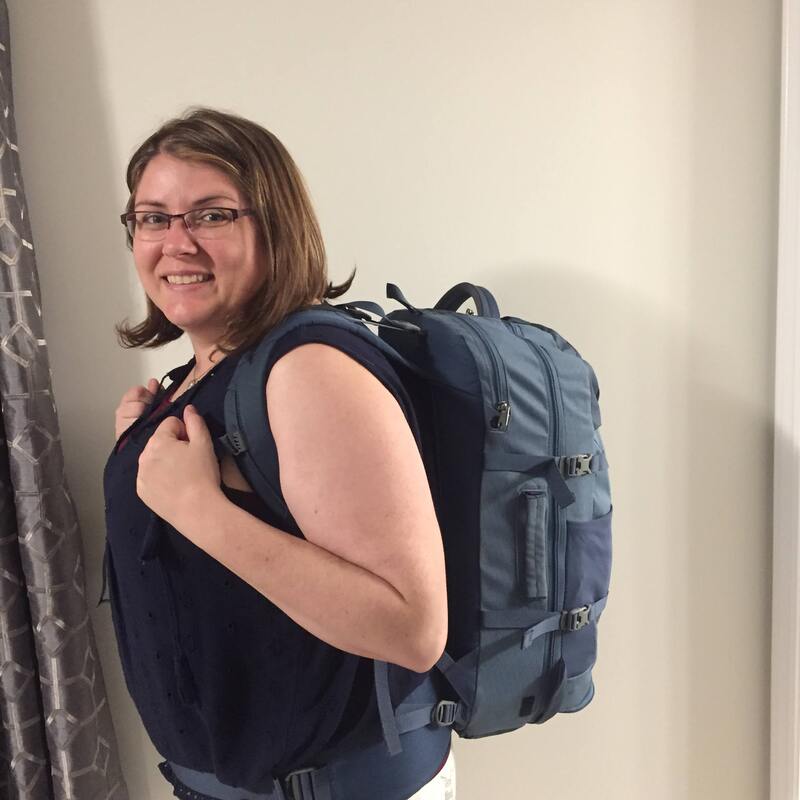 Vanessa wears a blue tank top and poses with a blue backpack