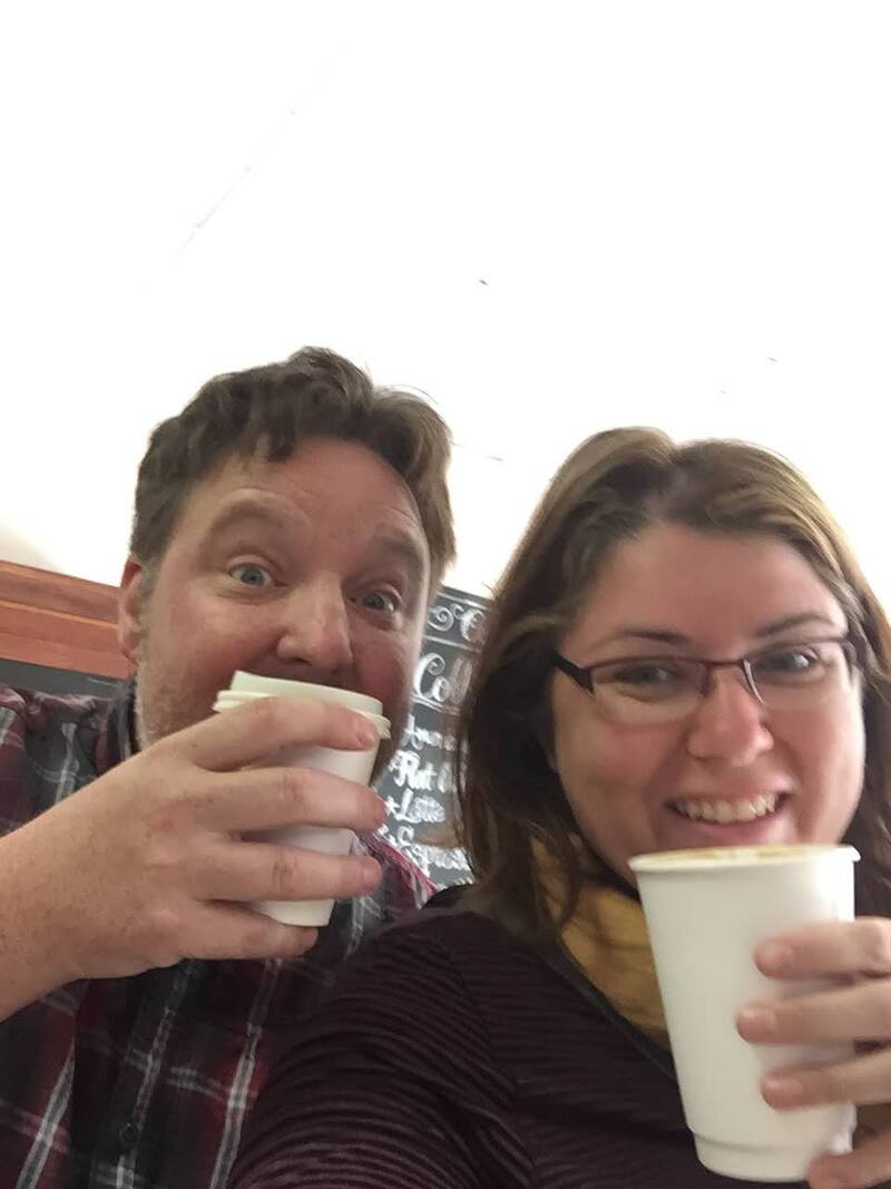 Ryan and Vanessa pose with cups of coffee.