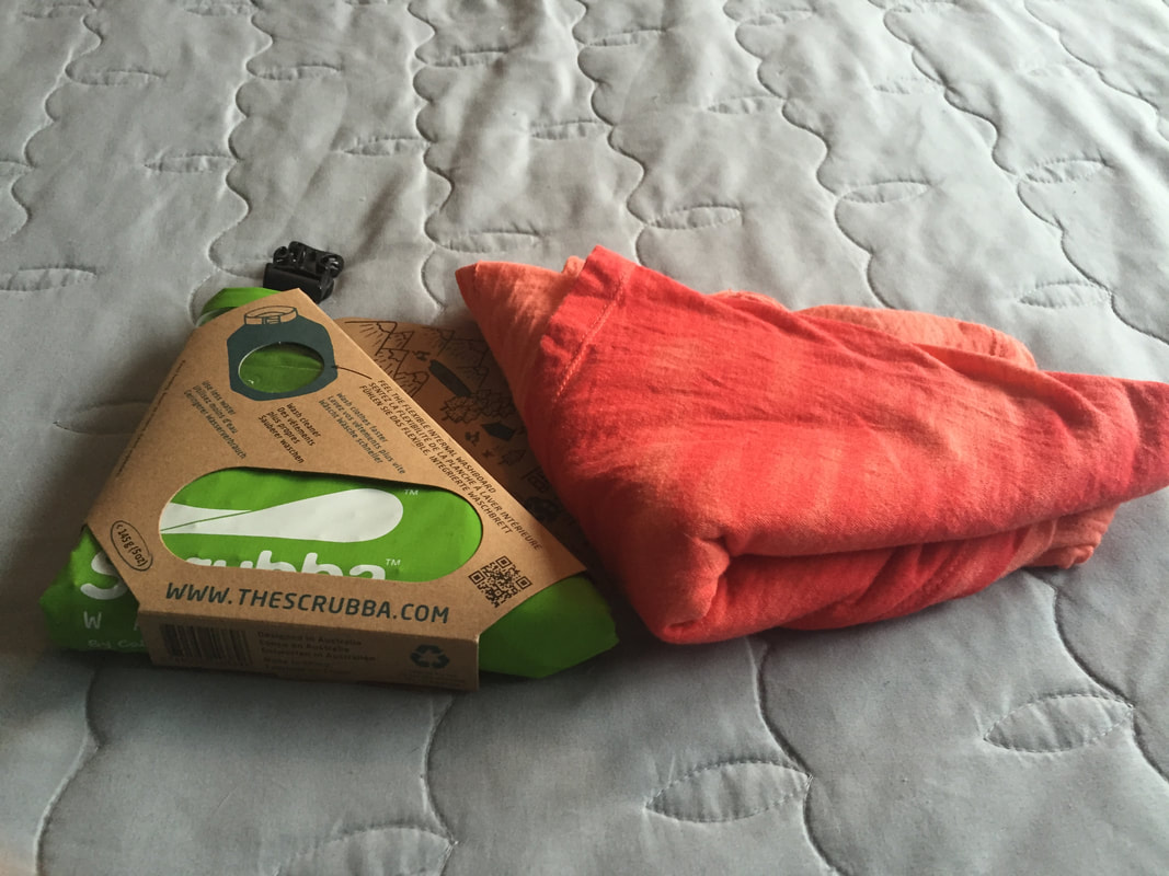Bright green Scrubba wash bag folded into a triangle and wrapped in a cardboard wrapper 