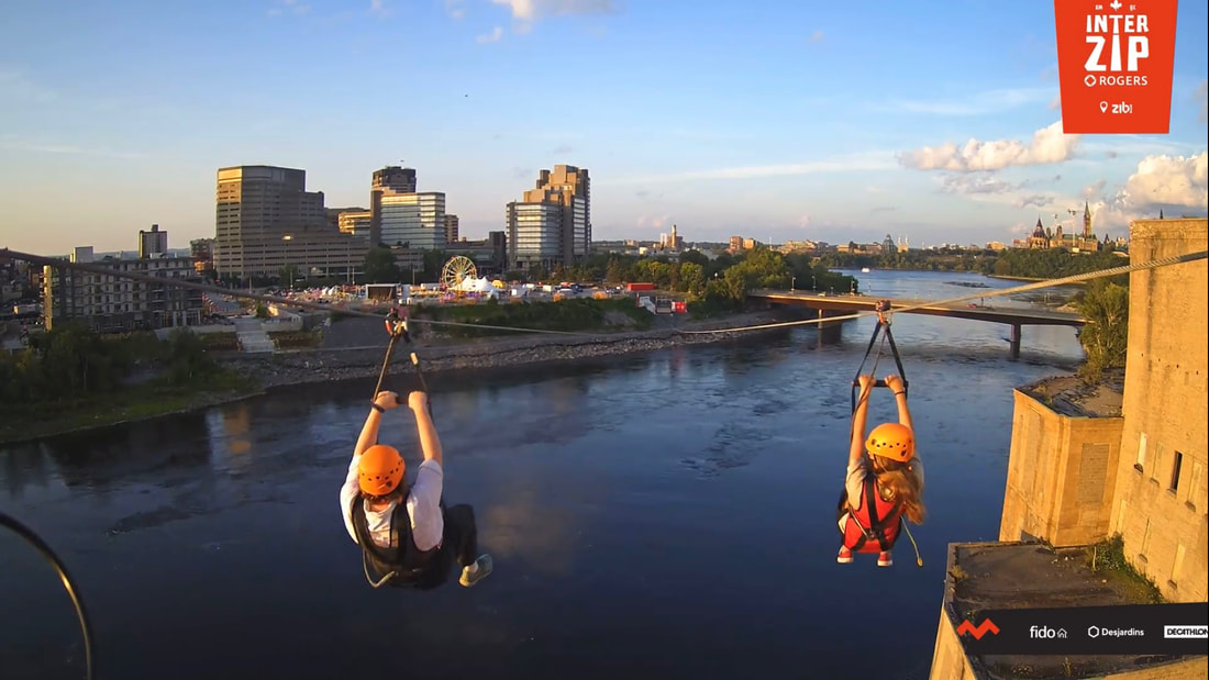 Vanessa and another woman start going down the zip line with views of the Ottawa River, Gatineau, and Parliament.