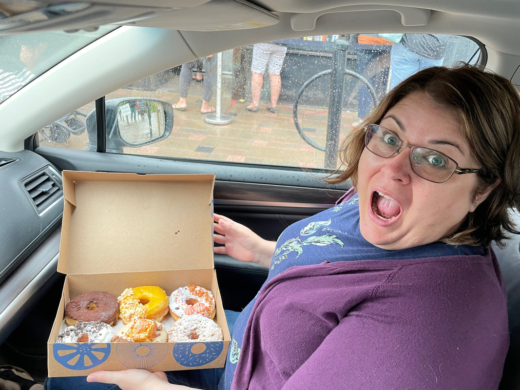 Ottawa bakeries: Vanessa sits in the car wearing a purple sweater, holding a box of colorful donutsPicture
