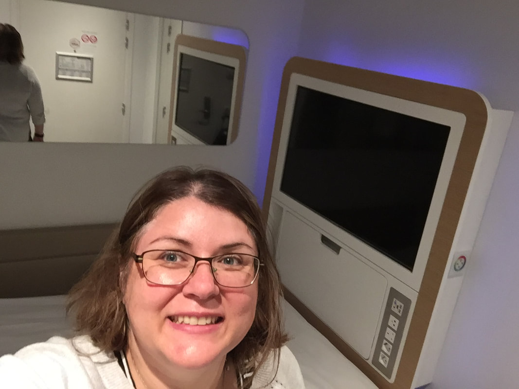 Vanessa takes a selfie in her airport sleeping pods, showing a white bed and walls.