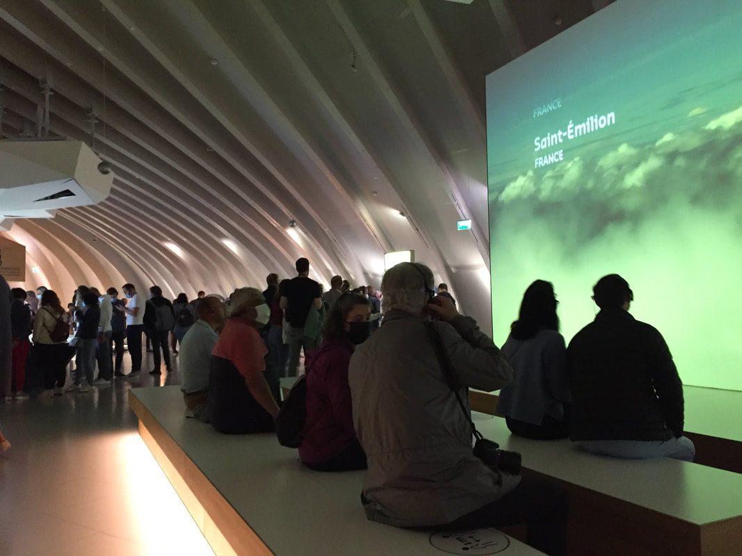 Inside the museum, people sit at a video presentation screen