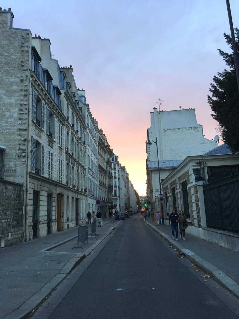 Dusk on a typical Parisian street with white buildings with shutters and attic windows