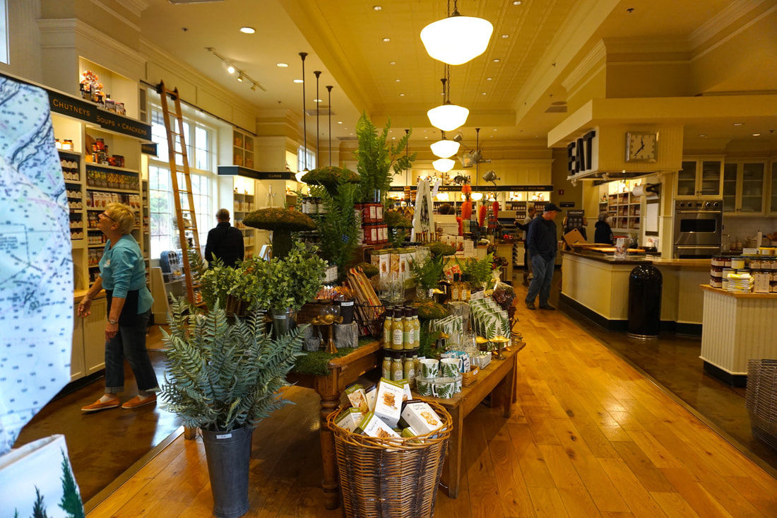 Inside of the store showing people shopping and busy displays of jams, jellies, snacks, and small decorative items.