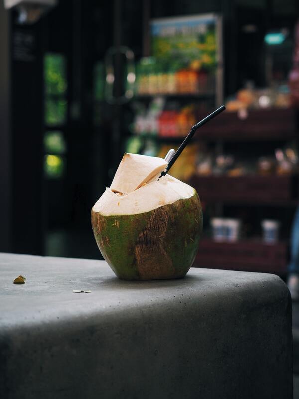 A green coconut prepped for sipping coconut milk, with a straw at the top