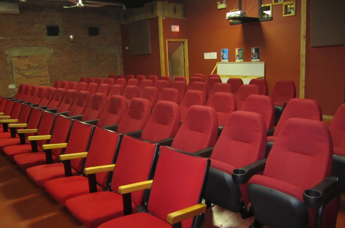 Long rows of red chairs in a small movie theatre