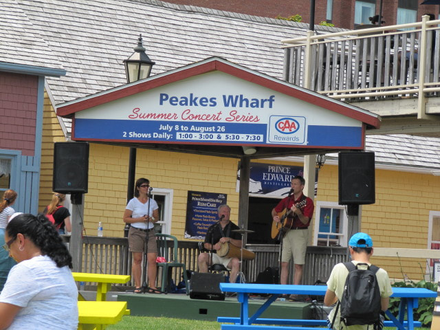 Musicians at an outdoor stage in from of a yellow building