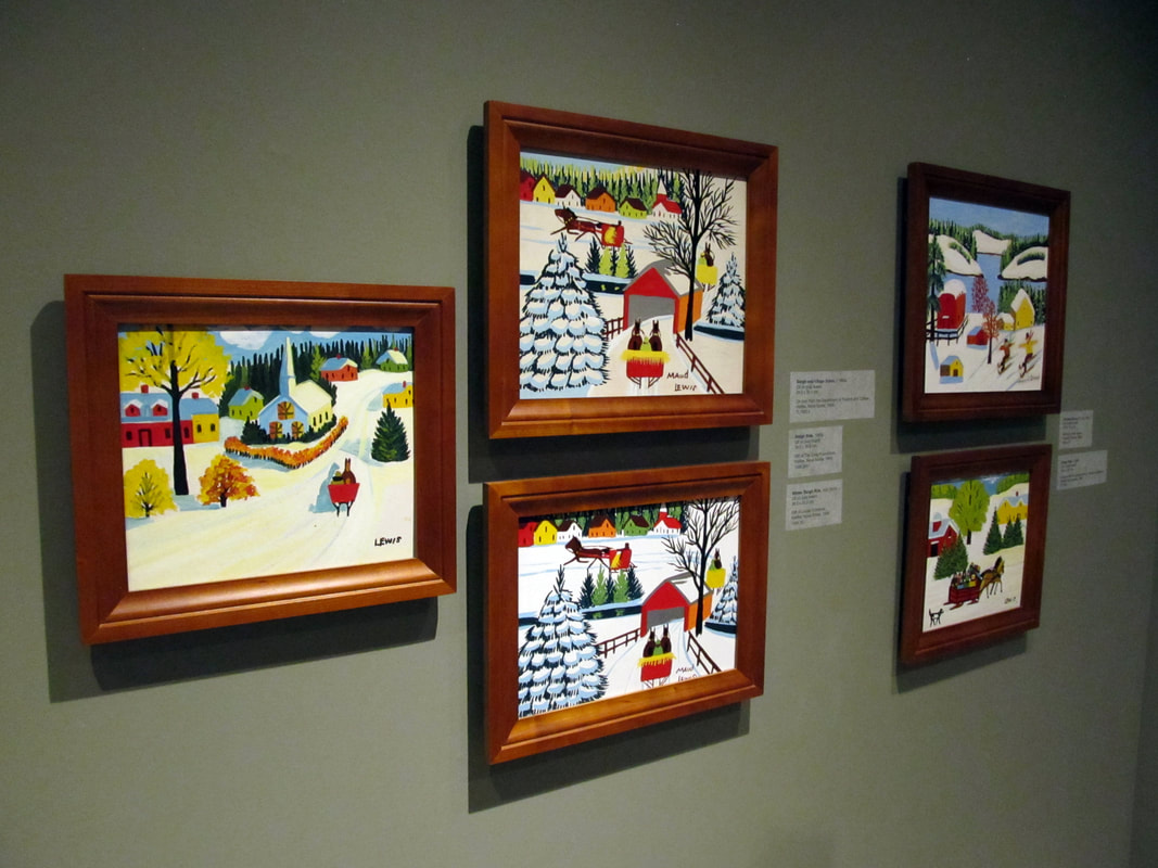Five colourful paintings by Maud Lewis hang on a gallery wall, framed with brown wood.Picture