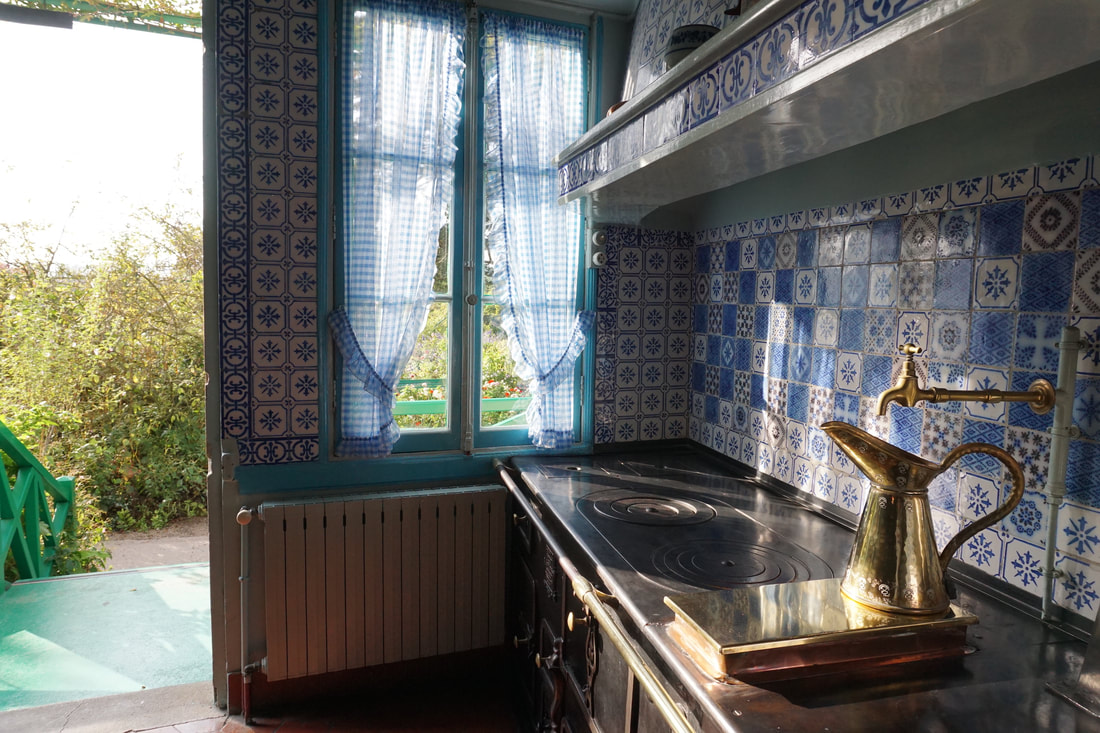An old fashioned kitchen with patterned blue tiles and a copper water pitcher