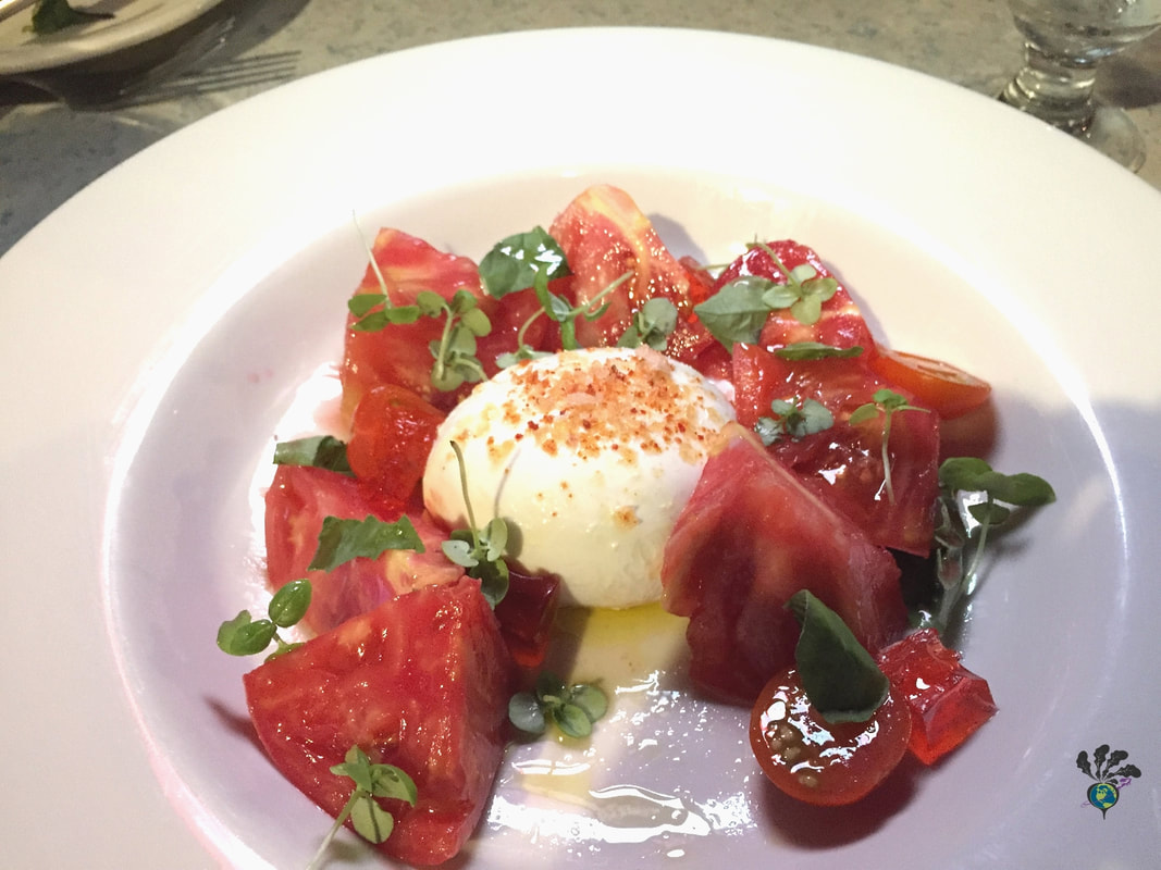 Belton chalet dining room bowl of chopped heirloom tomatoes surrounding a ball of burrata cheese
