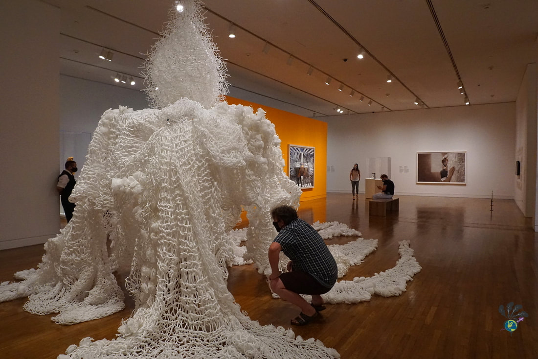 Ryan examines a large piece of white modern art fashioned from foam loops