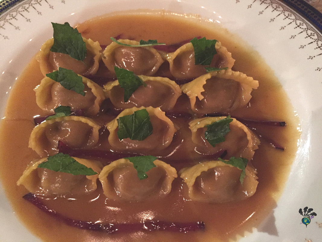 Stuffed pasta covered in mint and slivers of plum and a light brown buttery sauce
