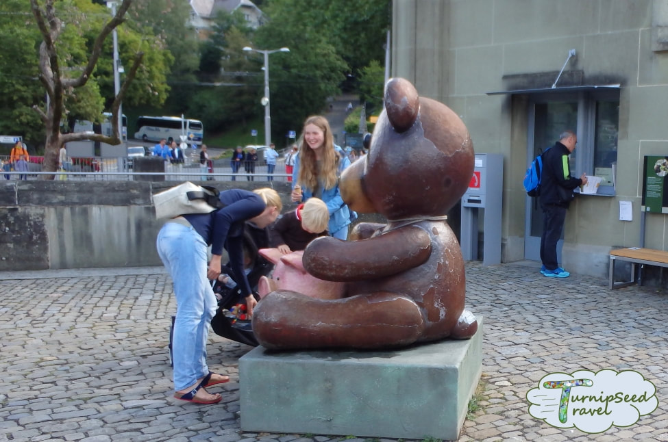 Children check out a large cartoon style sculpture of a brown bear