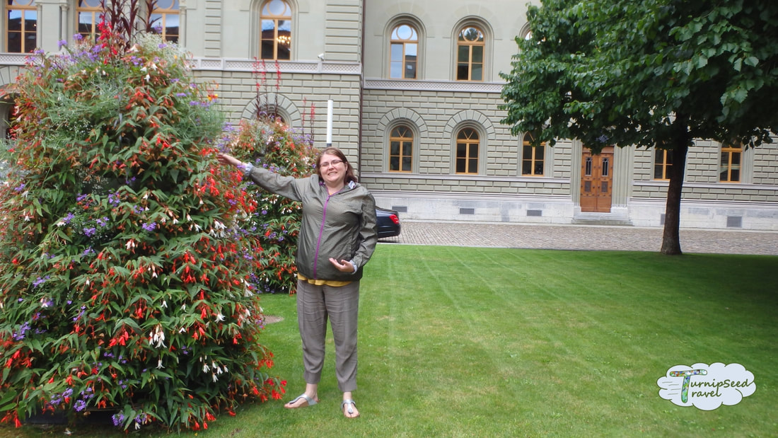 Things to do in Bern, Switzerland: Vanessa stands next to a large colourful bush with red white and purple flowers.