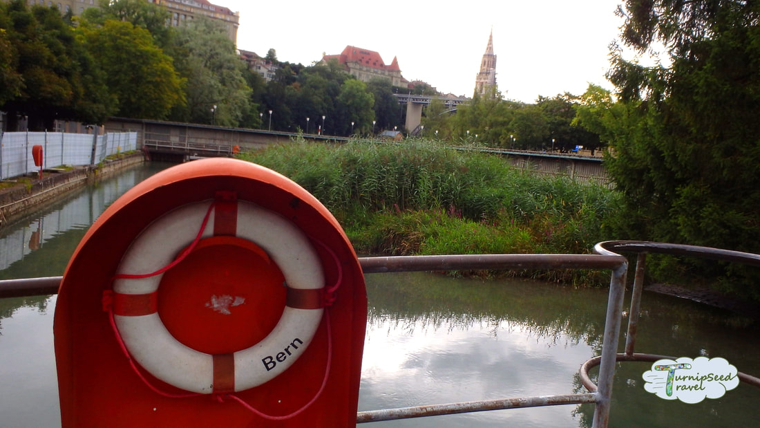 A look at the river and city beyond, with a white life preserver ring in the foreground