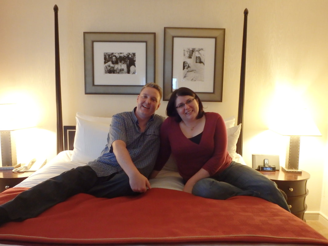 Ryan and Vanessa sit on a four poster bed
