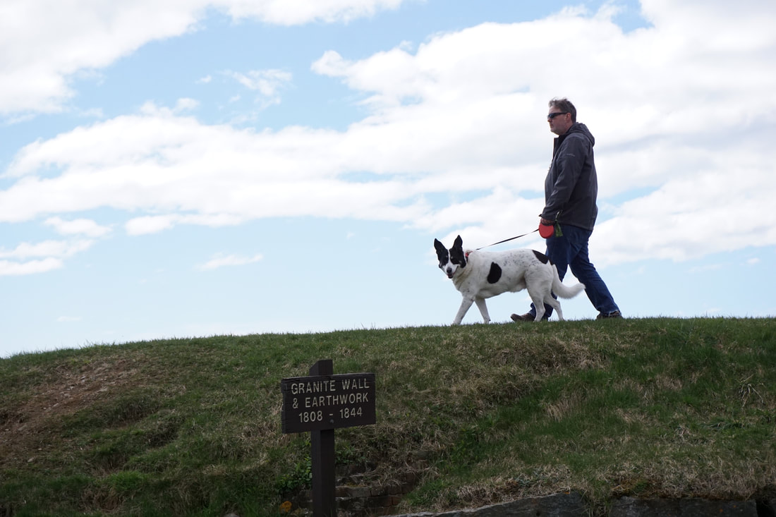 Things to do in Kittery: Ryan and Oliver walk on a earthen wall at Fort McClary, with blue skies behind them.
