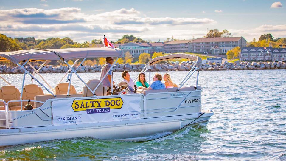 Passengers sit in a small white boat from Salty Dog Sea Tours, with the hotel and conference center in the background. Picture