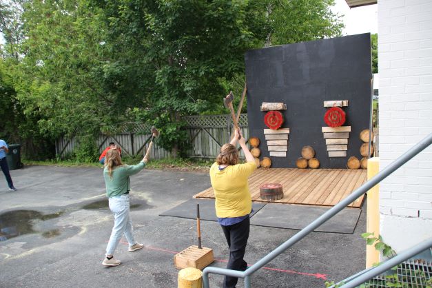 Vanessa and a friend get ready to throw their axes at the target