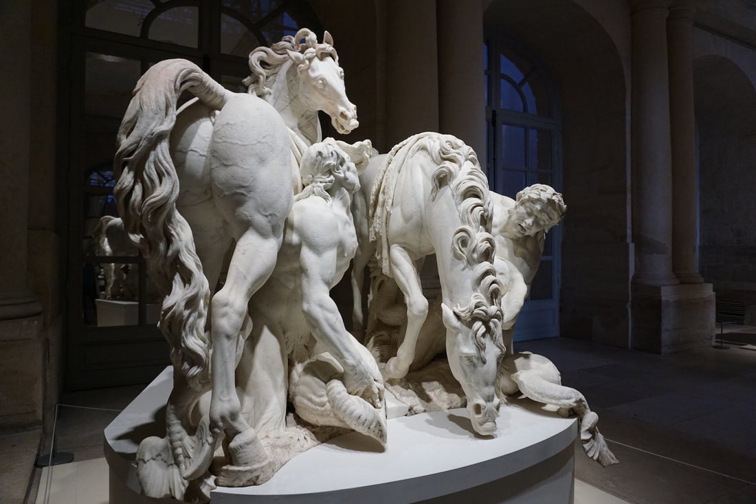 White marble statue of two horses and two men struggling