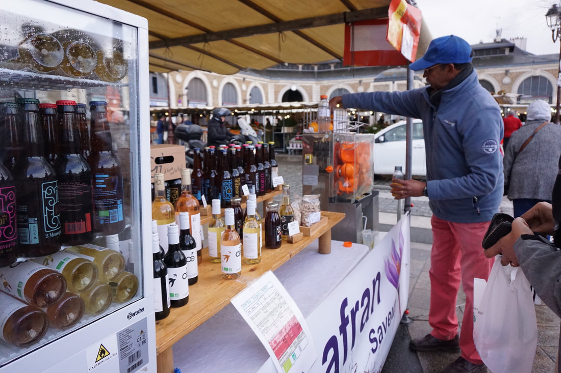 Wine and juice vendor operates a machine to press fresh oranges into juice