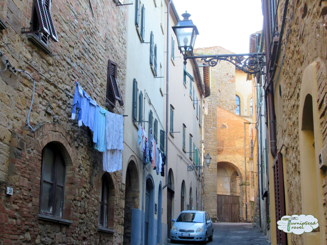 Colorful clotheslines along cobblestone streets in Volterra, one of the best Tuscan villages. 
