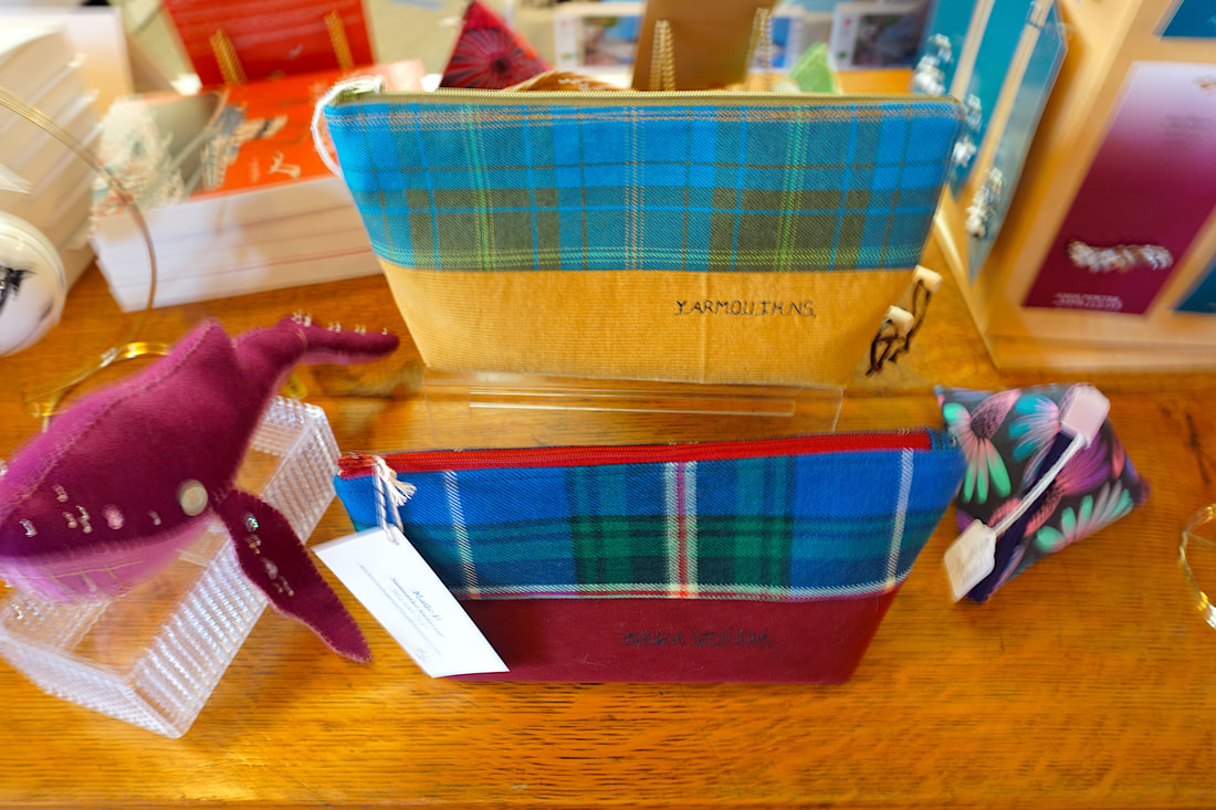 Slightly blurry photo showing pencil cases made from nova Scotia tartan and other gift shop items like books and ornaments. 