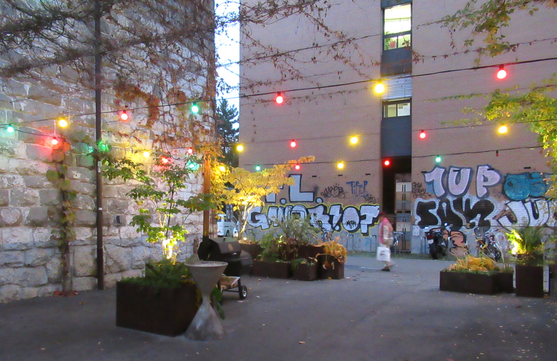 A courtyard with graffiti and colourful lights strung up.