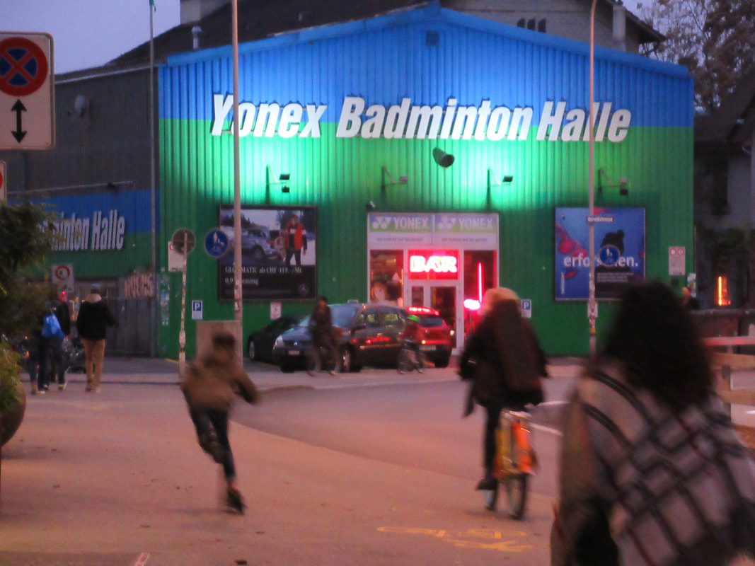 Things to do in Zurich: A blue and green badminton hall at dusk